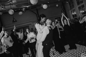 People dancing together at a party with paper lanterns overhead on a checkered floor in black and white photography.