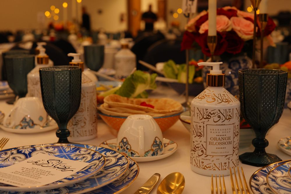 Formal dinner table setting with blue glassware and patterned plates in Middle Eastern style.