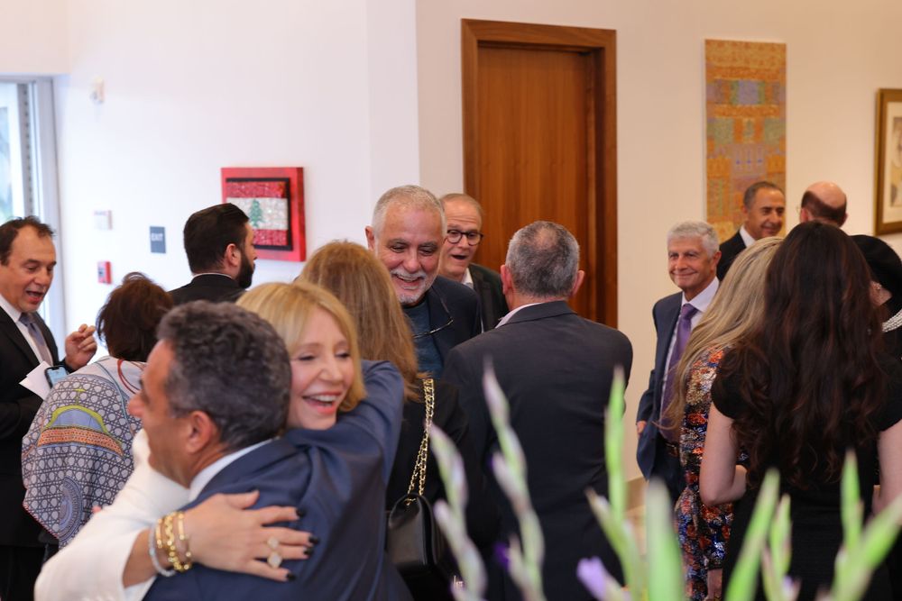 Crowded reception event with people mingling and socializing in a bright indoor space.