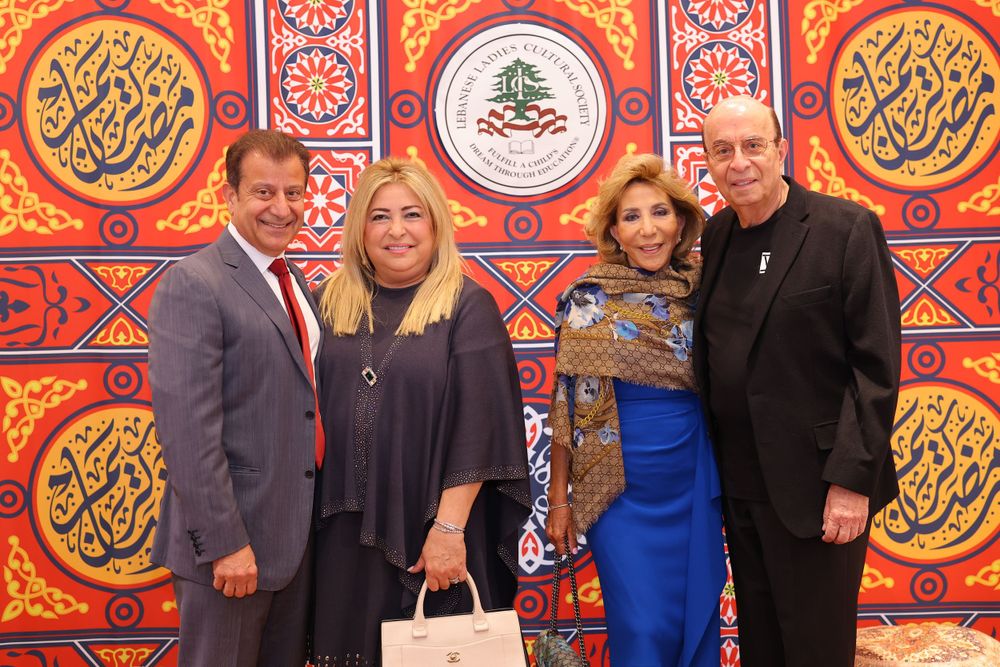 Group photo of four people in formal attire against decorative Middle Eastern backdrop.