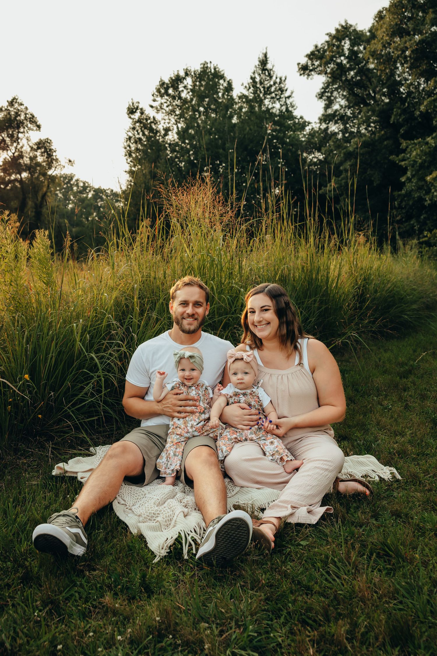 Family sitting in a grassy field holding their twin baby girls, boho family photography