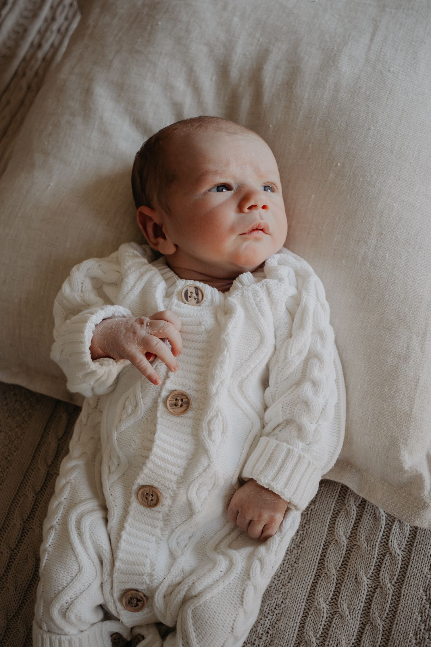 Newborn baby leaning on cushion.