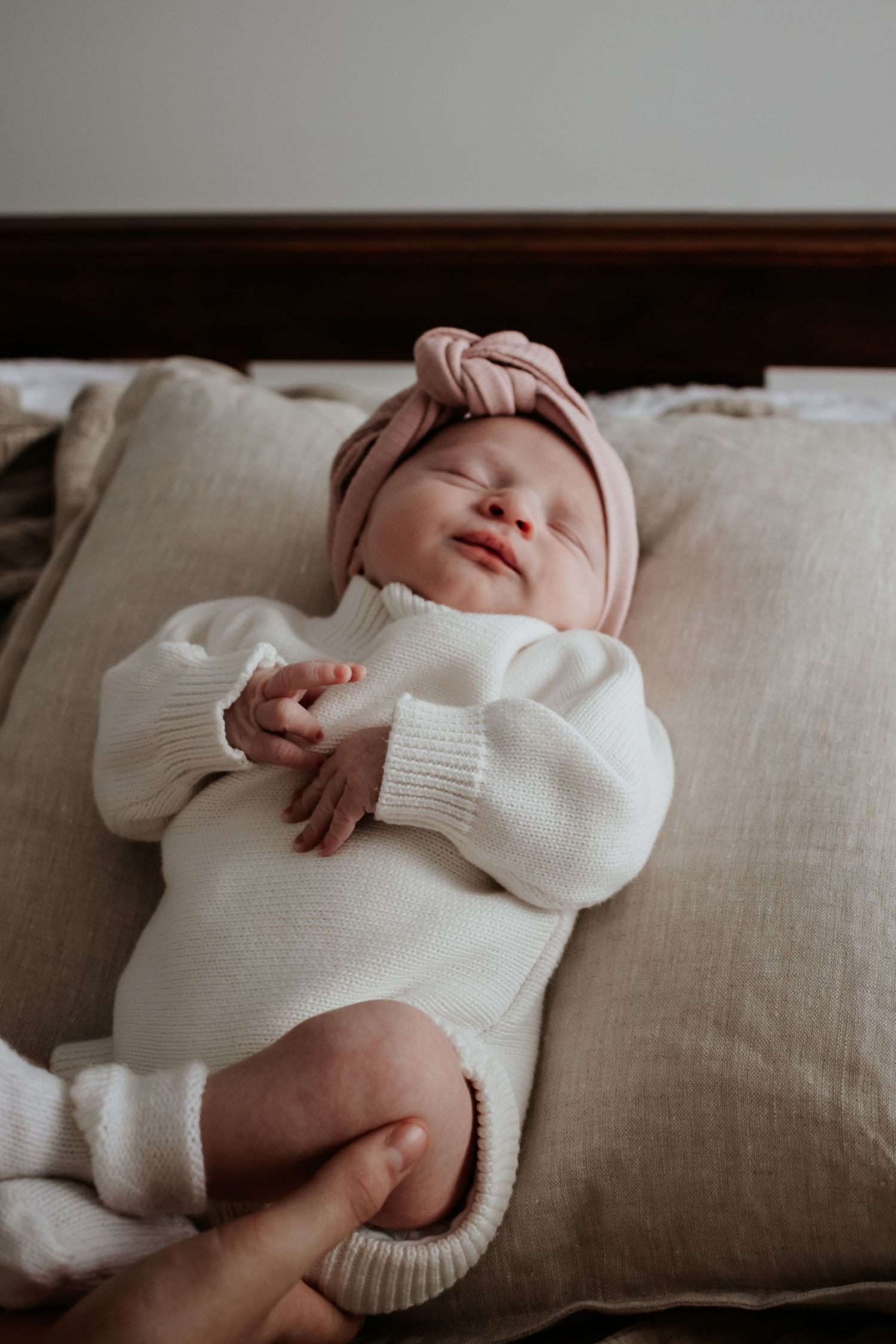 Newborn baby leaning on a cushion.