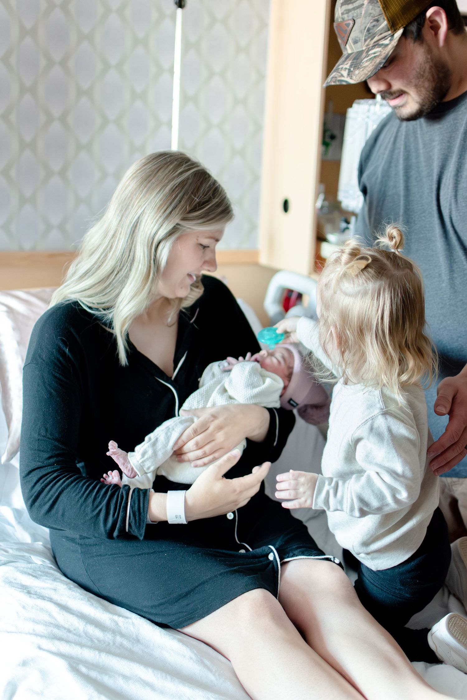 Family bonding with their newborn baby on a hospital bed.