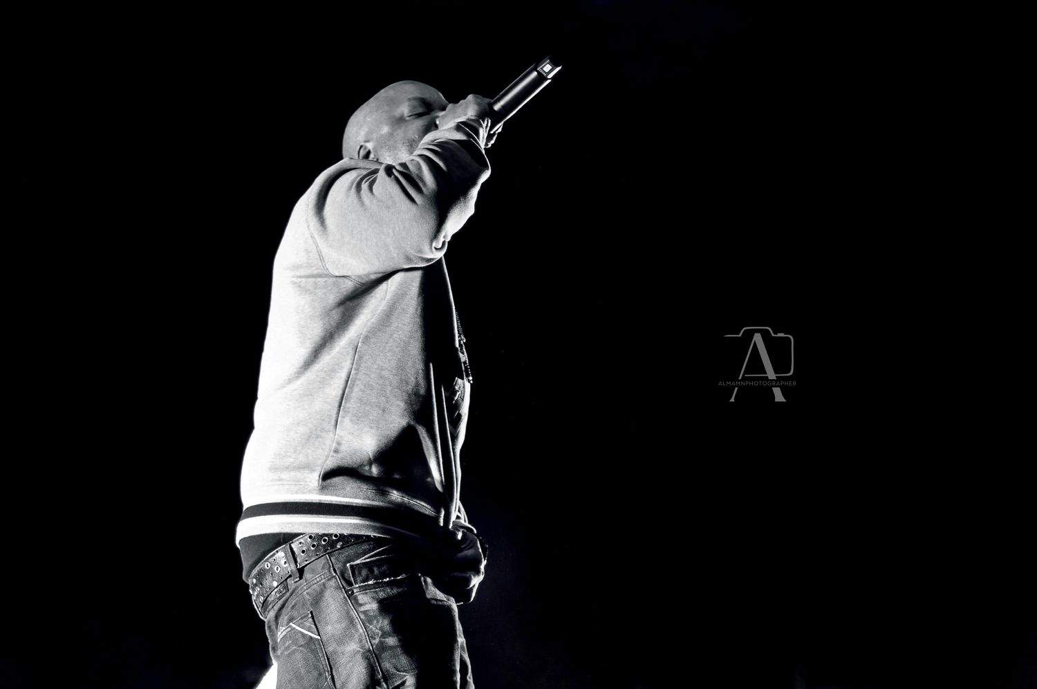 Dramatic monochrome performance shot of artist on stage with microphone.