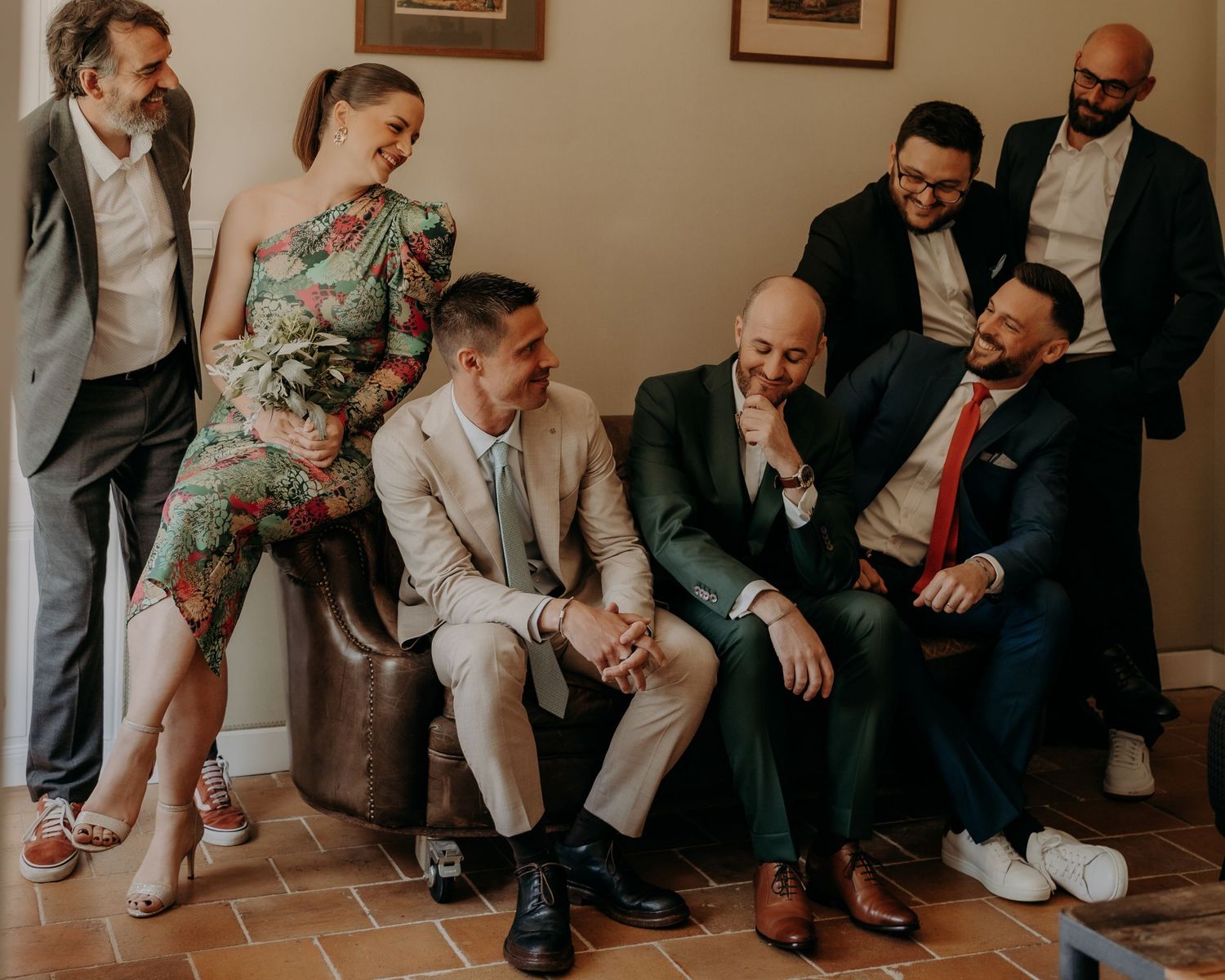Wedding guests seated casually on a bench sharing candid moments together.