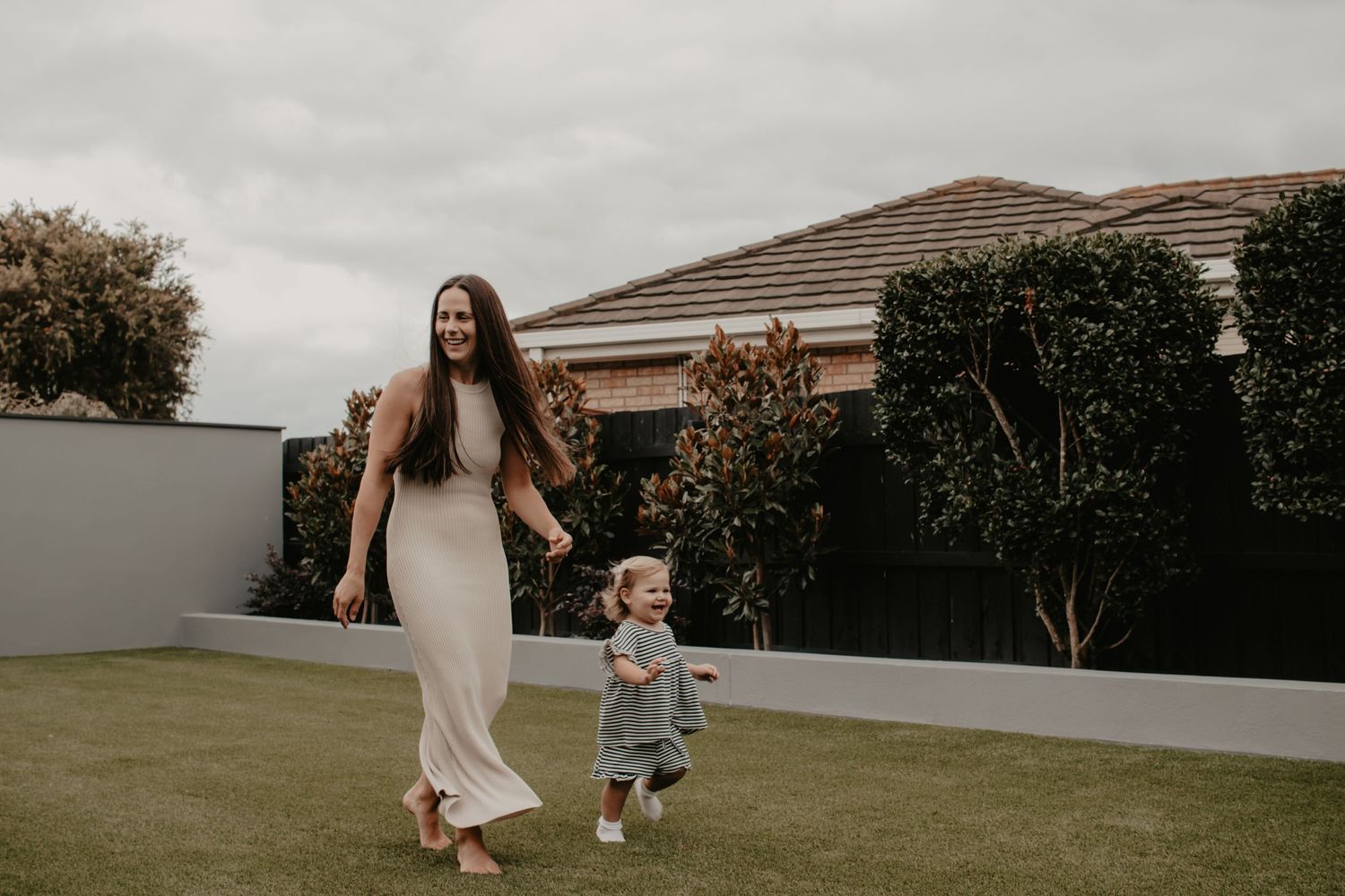 Mum and daughter running in the backyard.