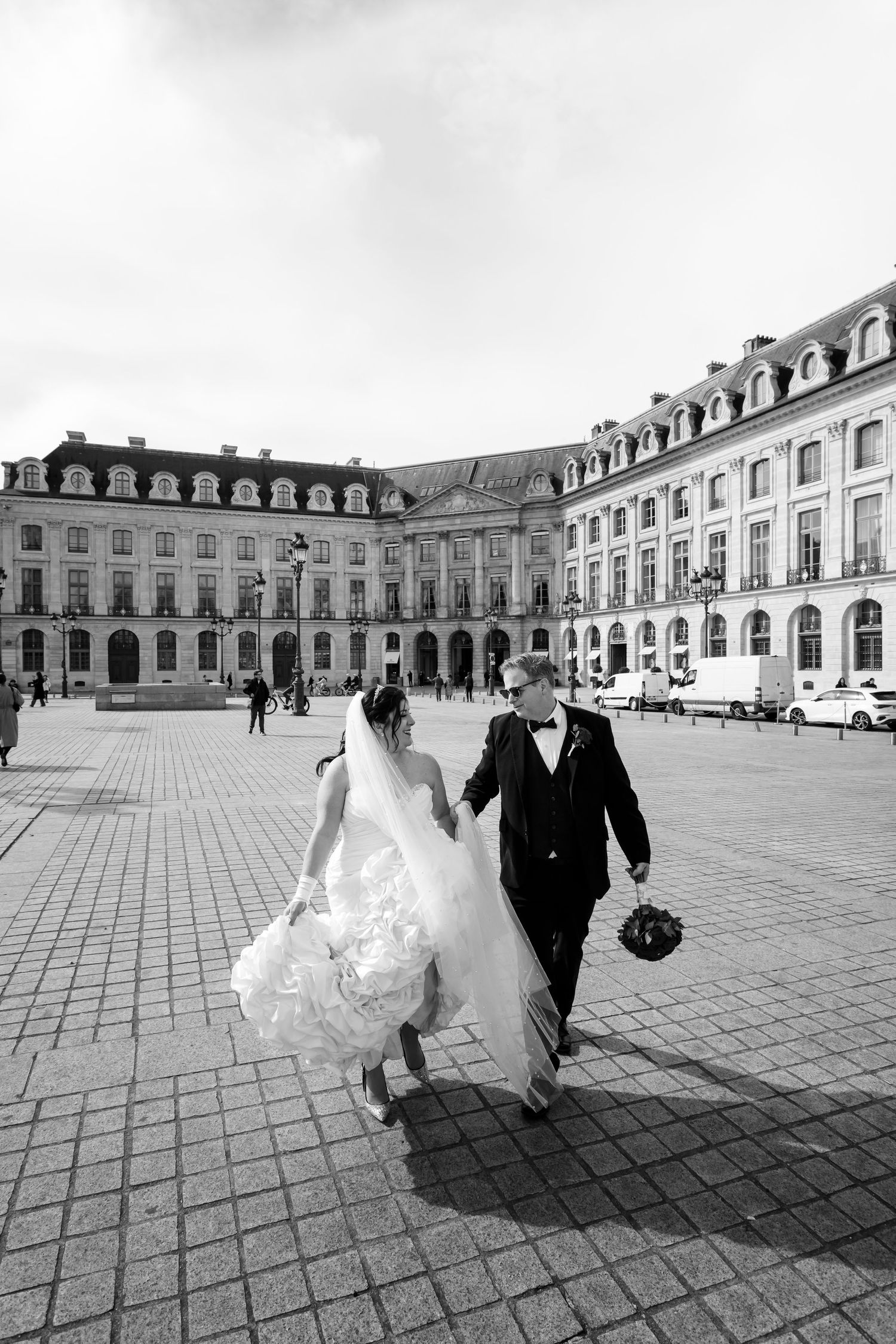 Elegant Parisian wedding: a radiant couple walking in front of the Ritz Hotel at Place Vendôme. Captured by Julien LB