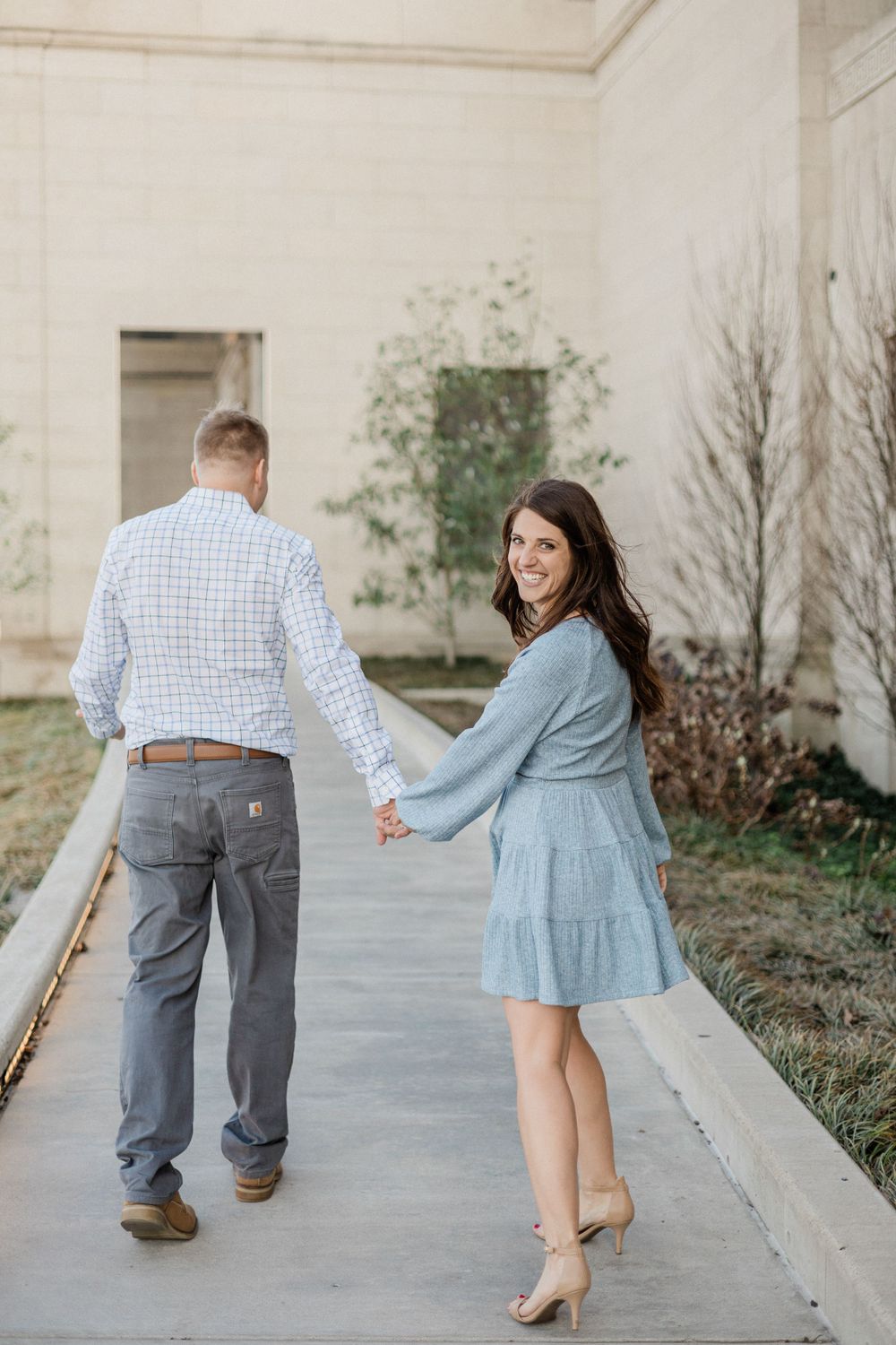 Couple walking together on a pathway dressed in coordinated blue and grey outfits.