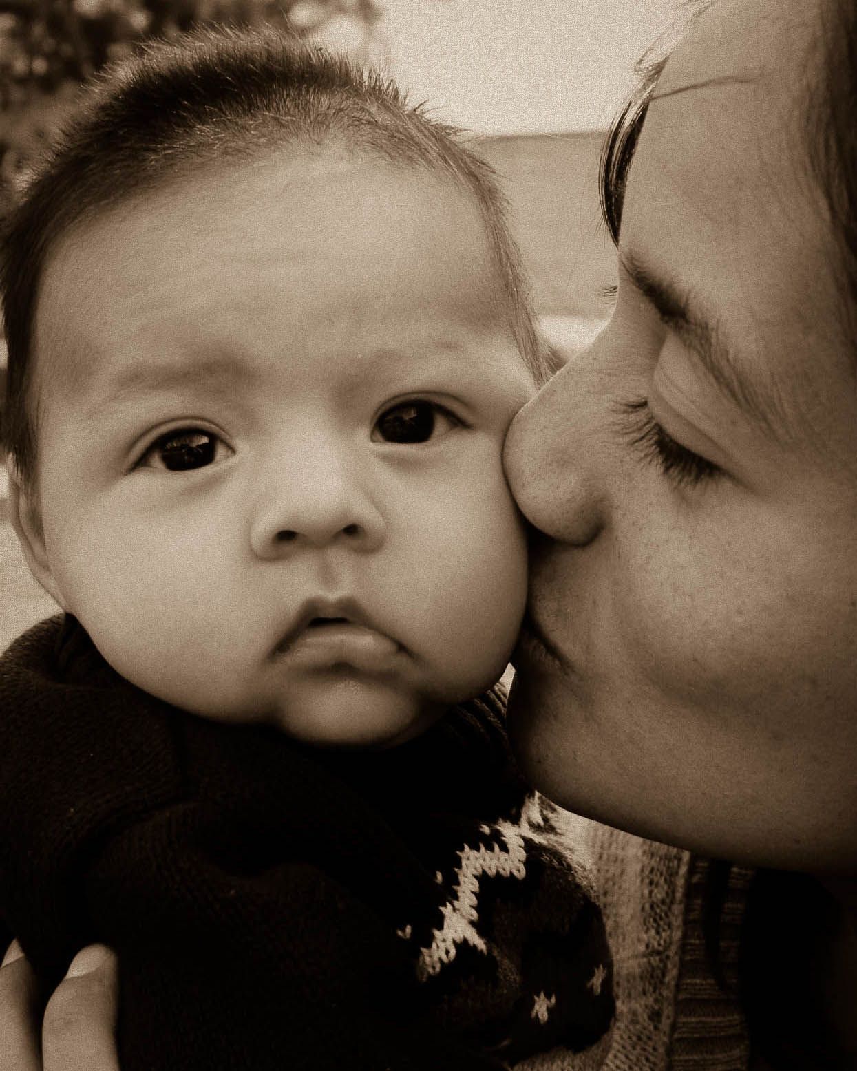 a mother kisses her young son