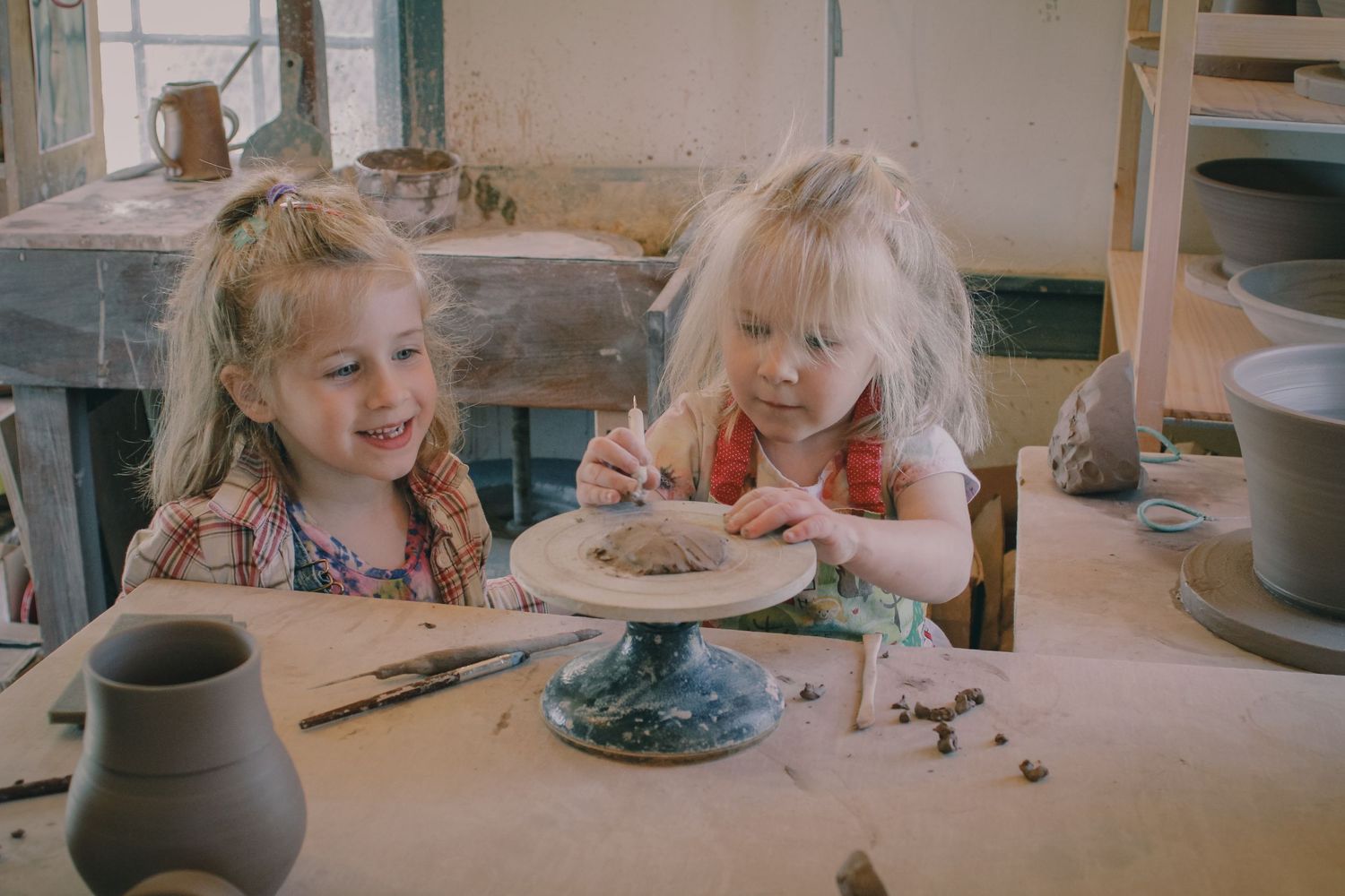 two girls build with clay, smiling