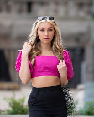 A person wearing a bright pink crop top and black skirt poses outdoors in a fashion photography series.