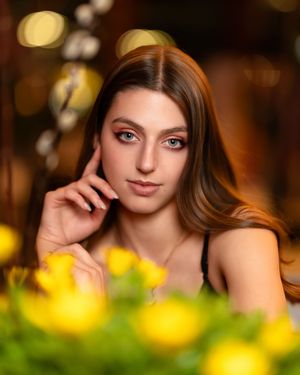 Portrait photo with soft bokeh lighting and yellow flowers in foreground creating warm ambiance.
