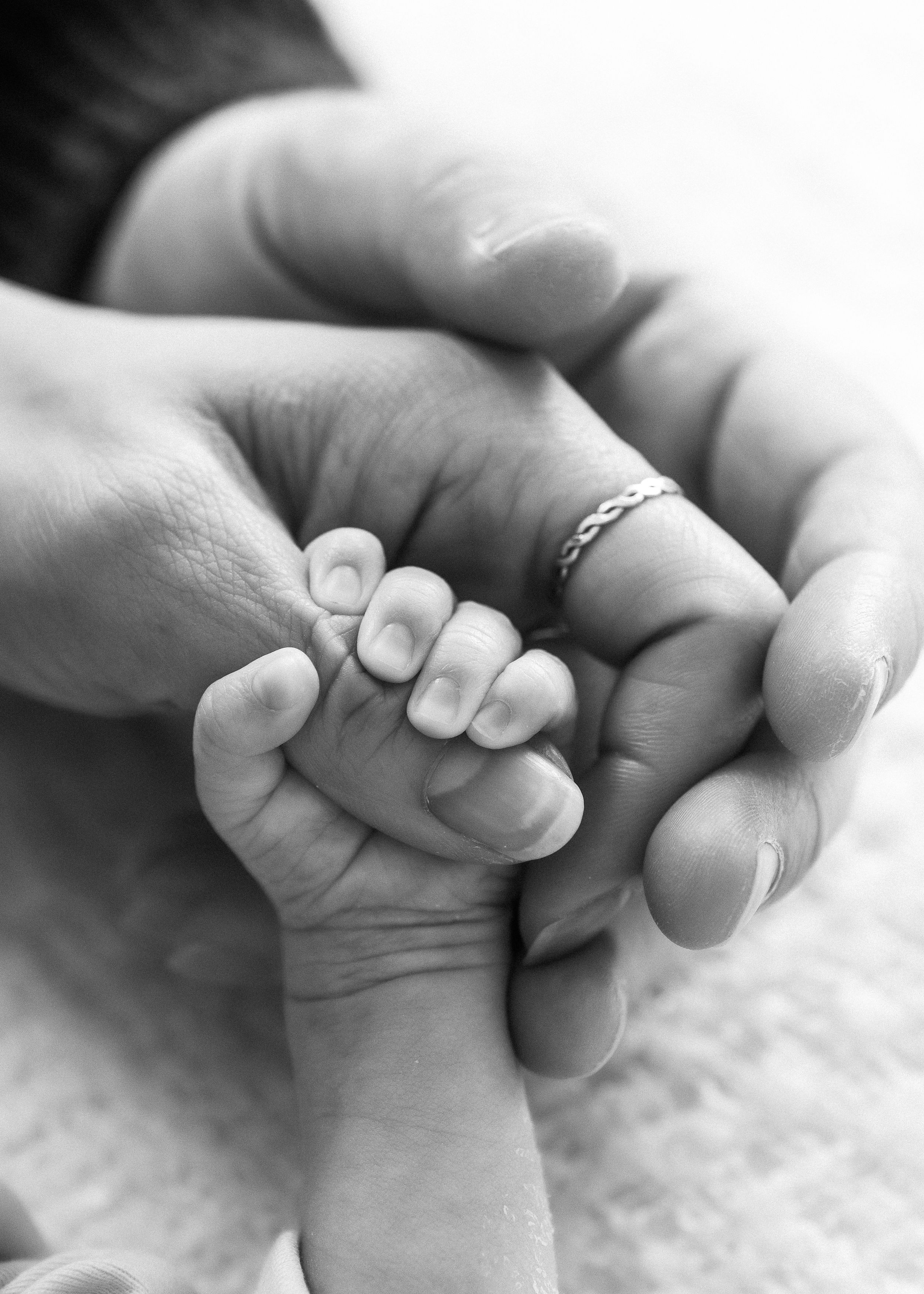 black and white close up of parents holding newborn hand natural connection Halifax