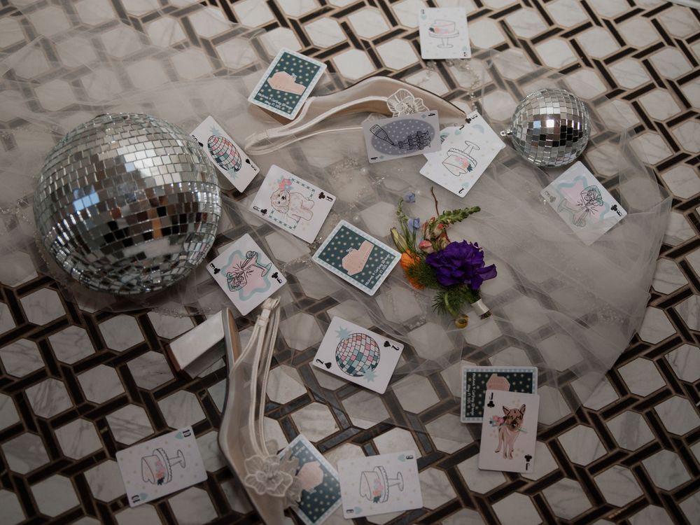 Disco balls and playing cards scattered on a marbled surface reflect light creating a festive party atmosphere.