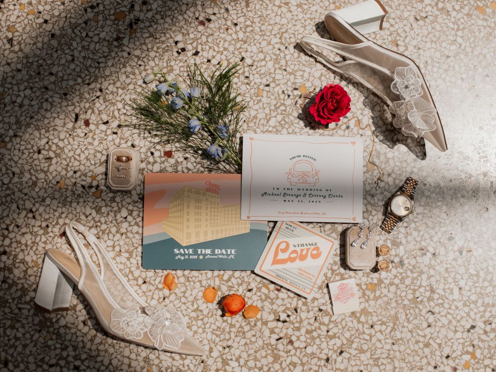 A collection of wedding invitation cards and envelopes arranged artistically on a speckled beige surface.