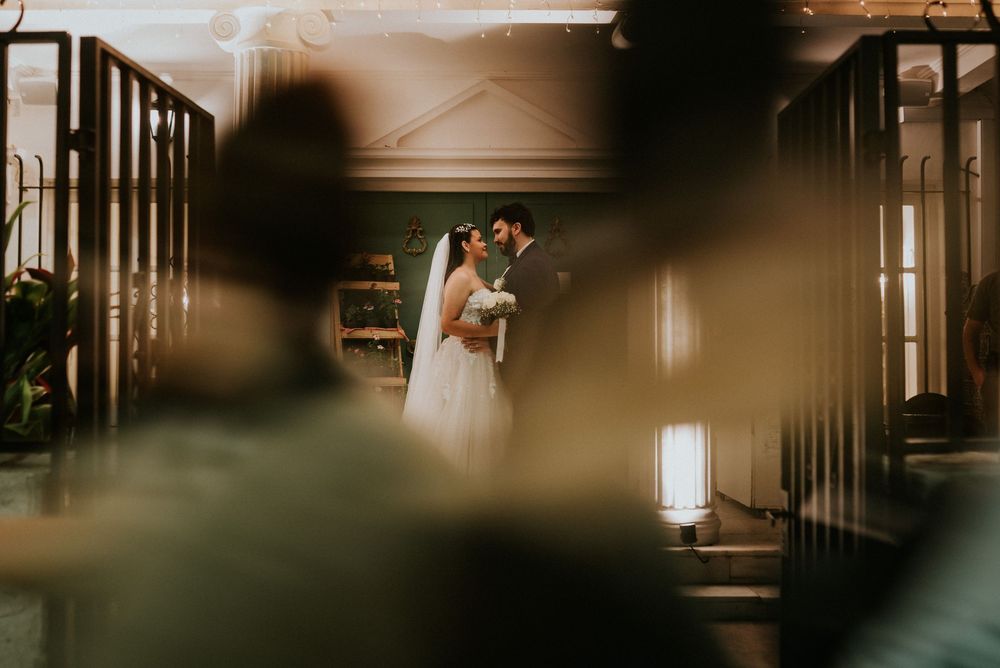 A couple shares a romantic first kiss at the altar during their elegant indoor wedding ceremony.