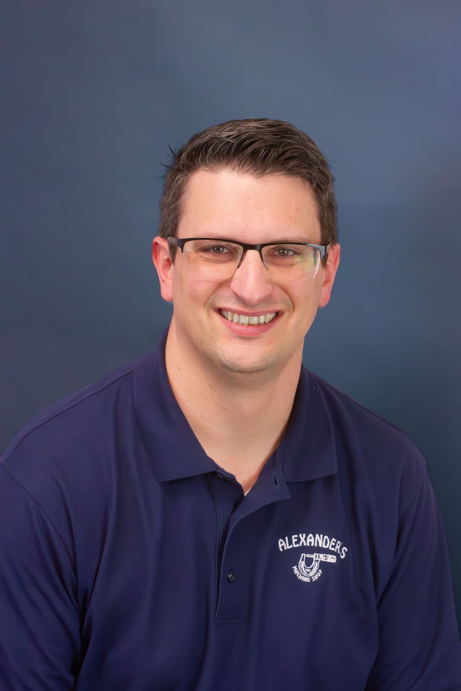 A man smiling in front of a blue backdrop for a professional head shot by Delta Blossoms Photography in Jonesboro Arkansas