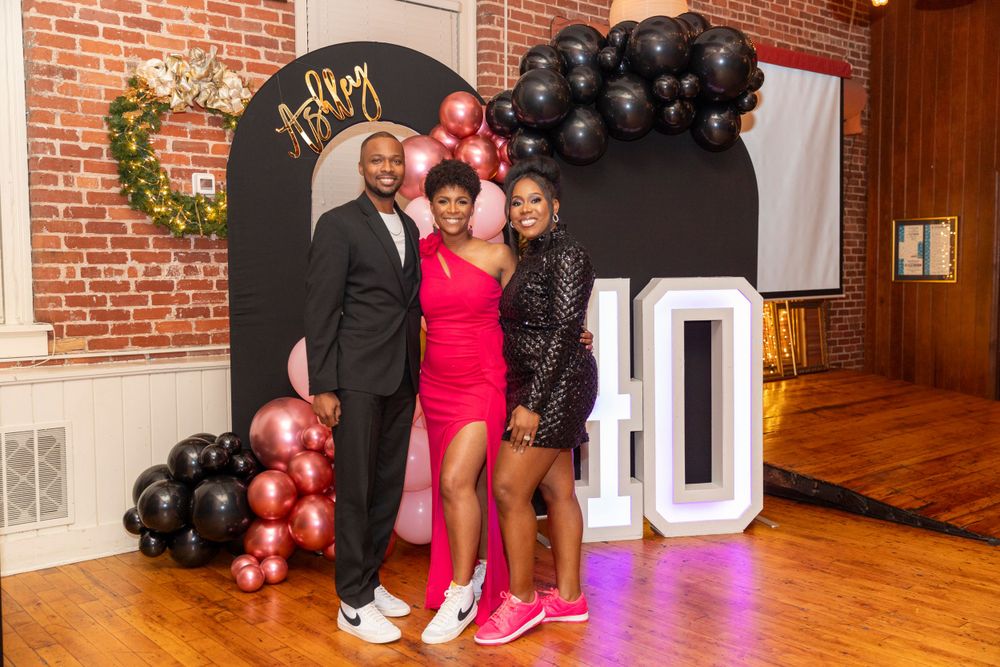 Celebratory event with black and red balloon decorations and illuminated signage.