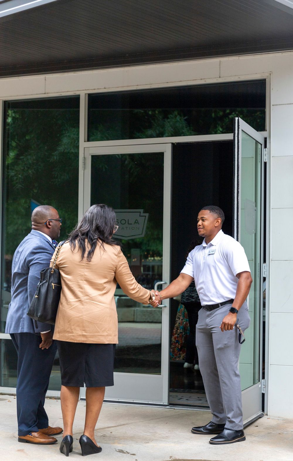 Professional greeting at building entrance with handshake.