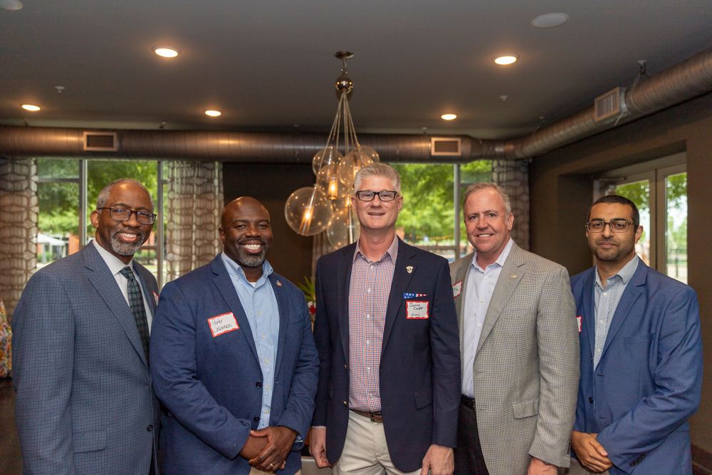 Business professionals in suits networking at indoor corporate event.
