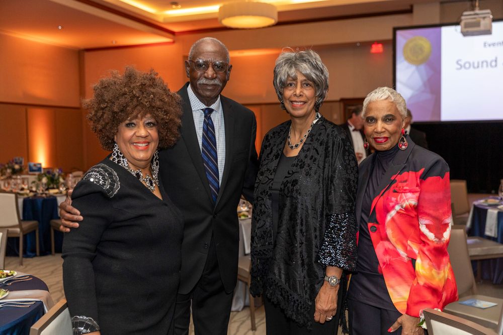 Attendees pose together at an elegant indoor social gathering.