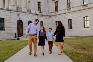 A group in business casual attire walks together on a pathway outside an elegant government or university building.