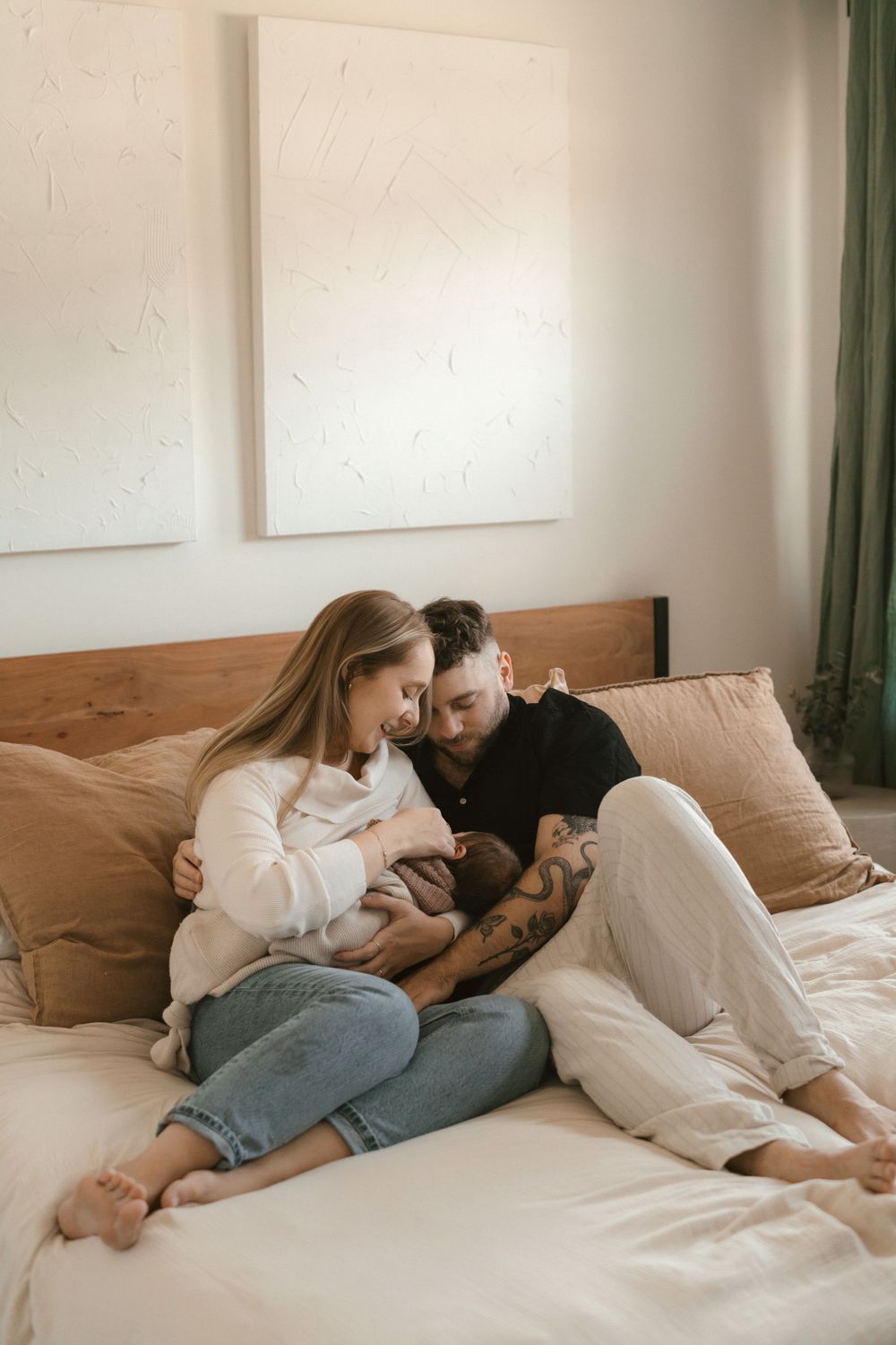 Intimate moment shared with newborn baby on a cozy bed with neutral tones.