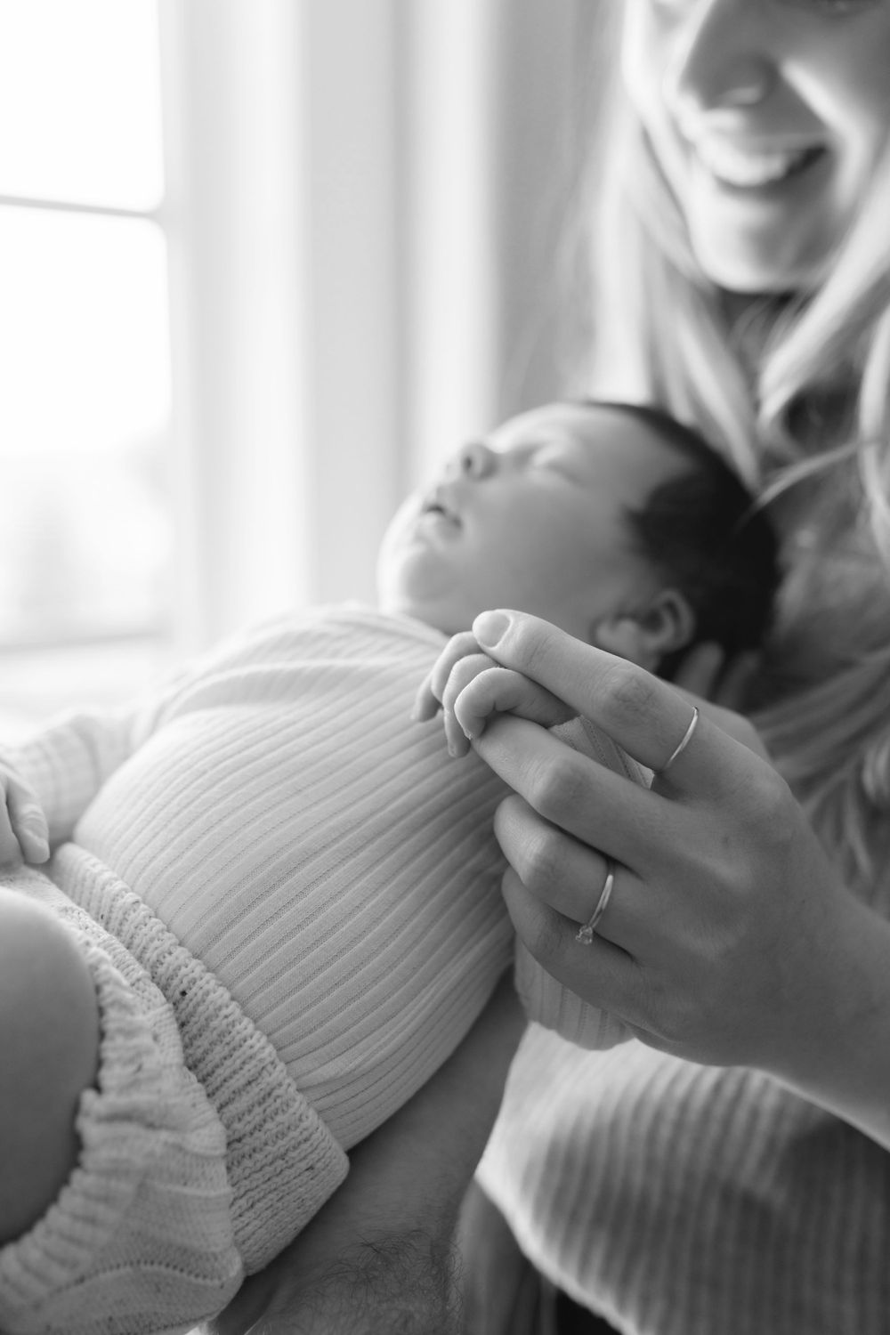 A peaceful black and white image of a baby sleeping while being held in gentle arms.