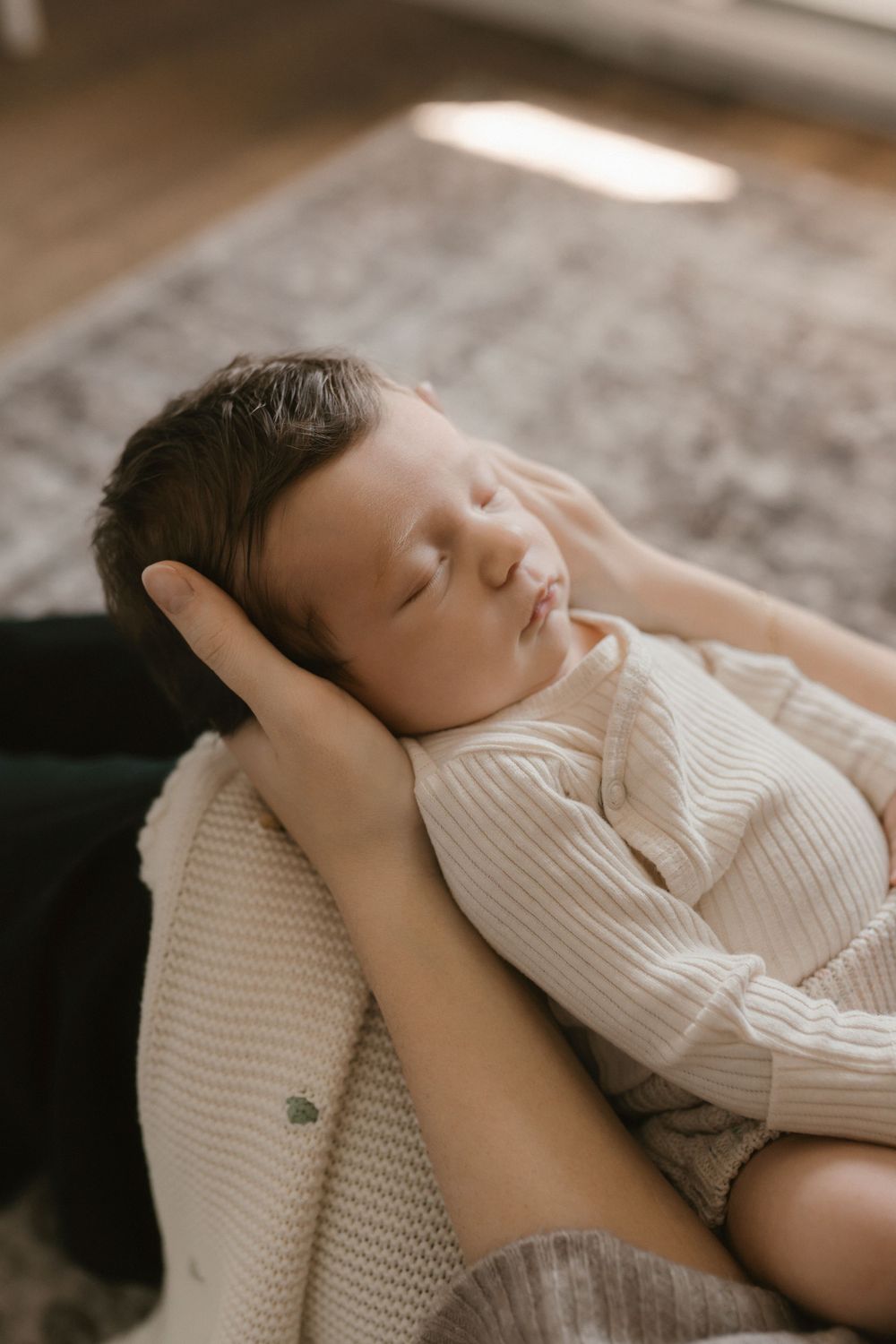 A sleeping baby in white clothing rests peacefully on a textured blanket.