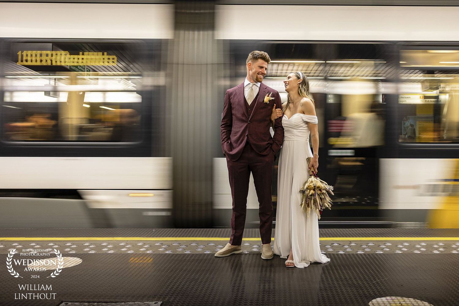 Creative wedding photo at subway platform with motion blur of passing train.
