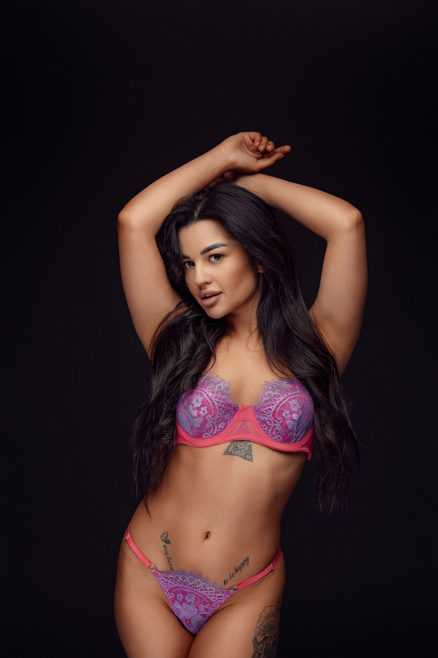 Fashion model wearing purple lace lingerie set with visible tattoos.