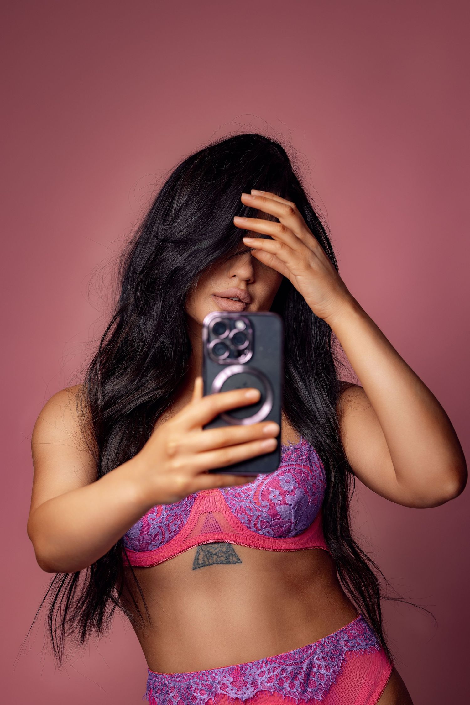 Person in purple lace lingerie takes selfie while covering face.