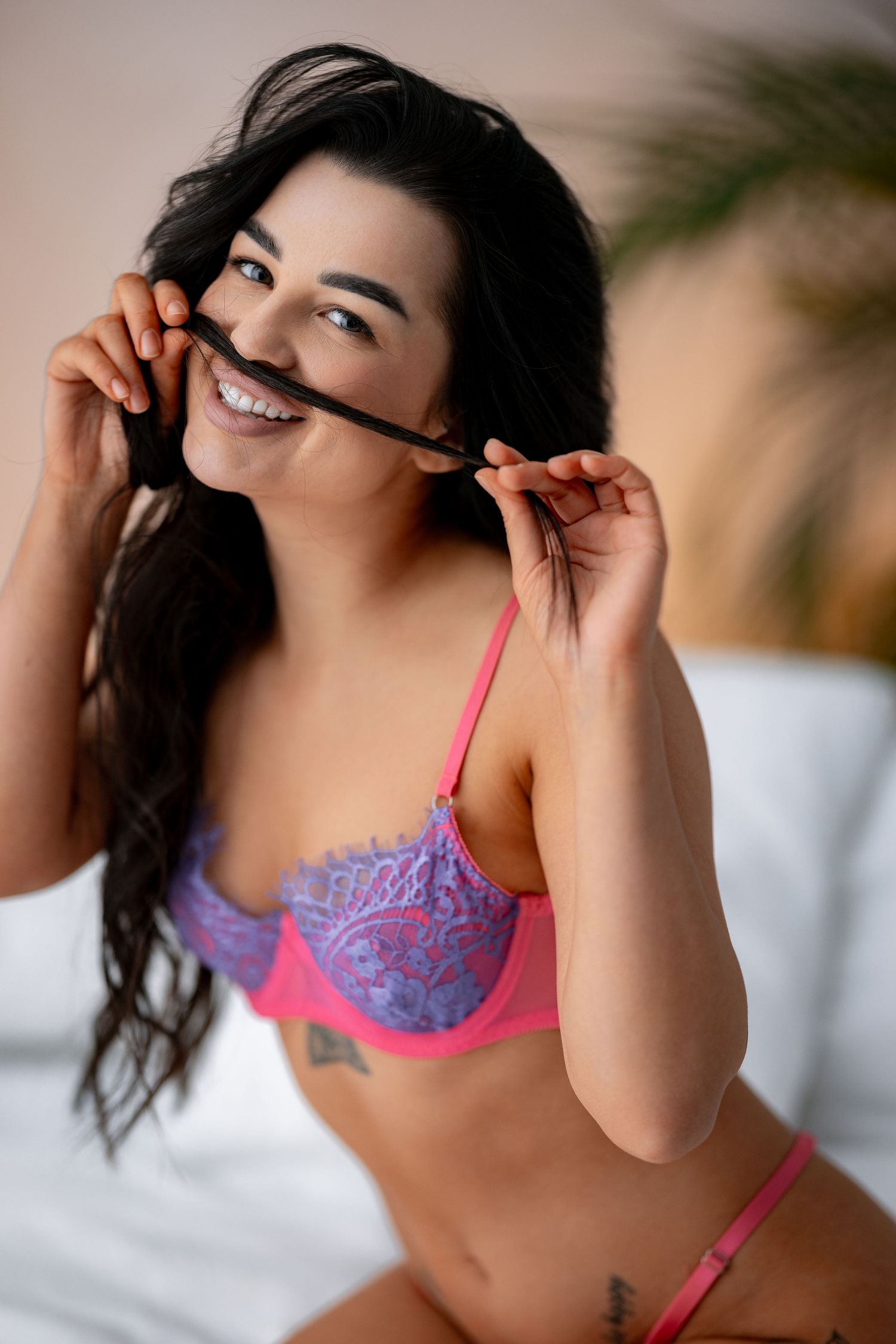 Playful boudoir photo featuring pink and purple lingerie against a light background.