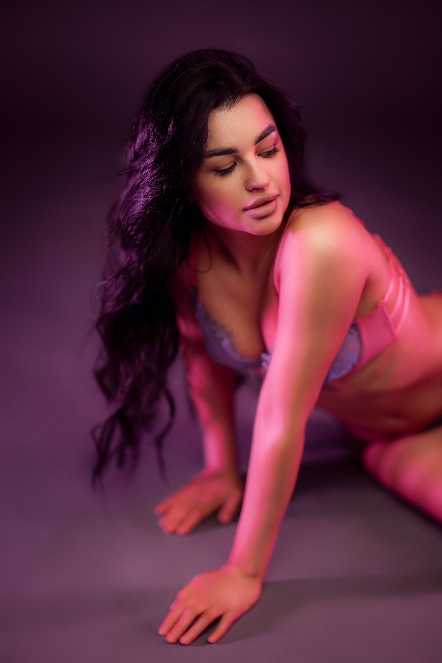 Figure in purple lingerie poses on floor with pink lighting effects.