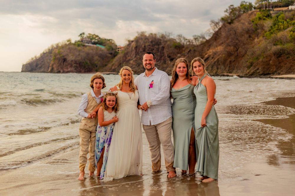 Bride and groom posing with family members on a scenic tropical beach at golden hour. Guanacaste, Costa Rica
