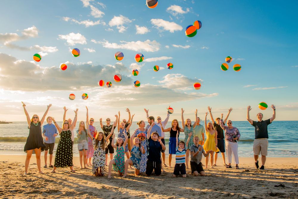 Large group of joyful people tossing colorful beach balls at sunset on a tropical beach. Guanacaste, Costa Rica