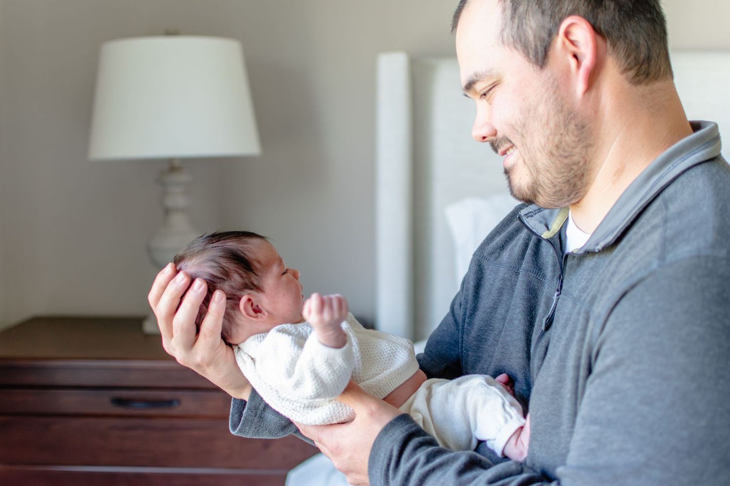 Dad cradle's baby girl's head as he looks at her.