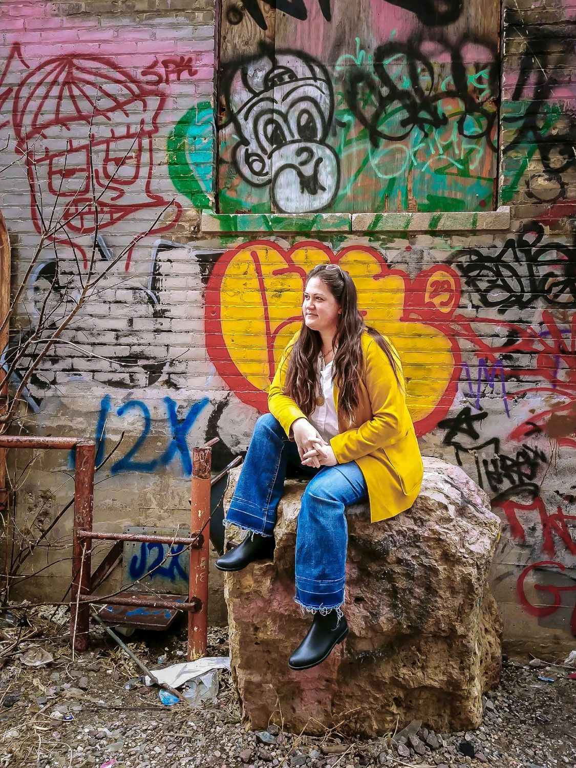 Photographer Heather Kowalski sitting by a wall of graffiti.