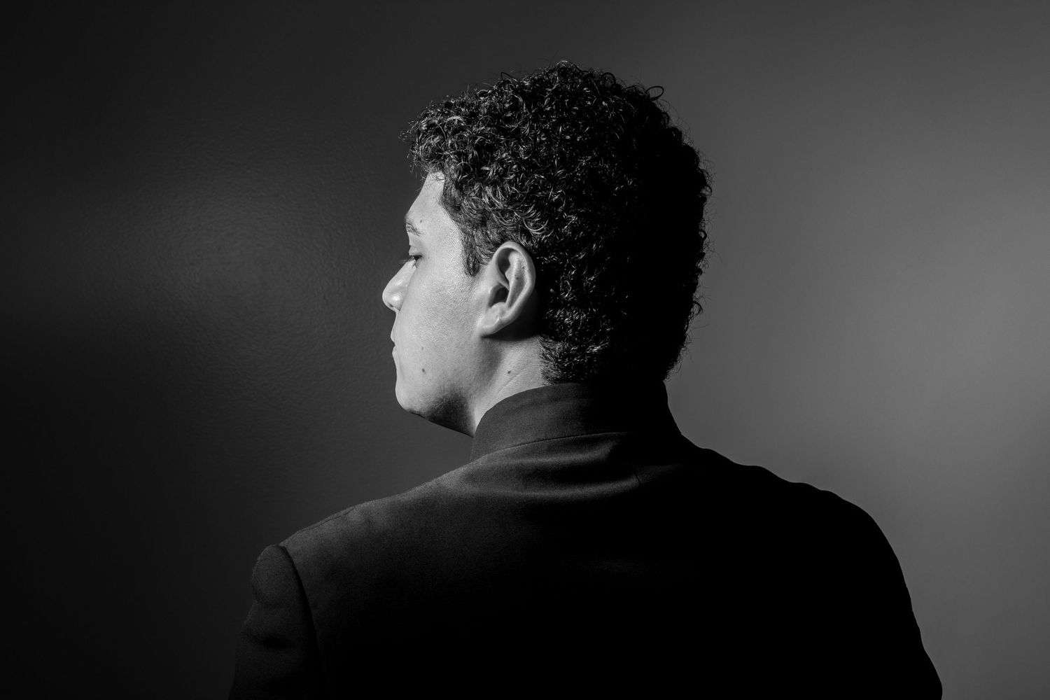 Dramatic black and white profile portrait of conductor in formal attire.