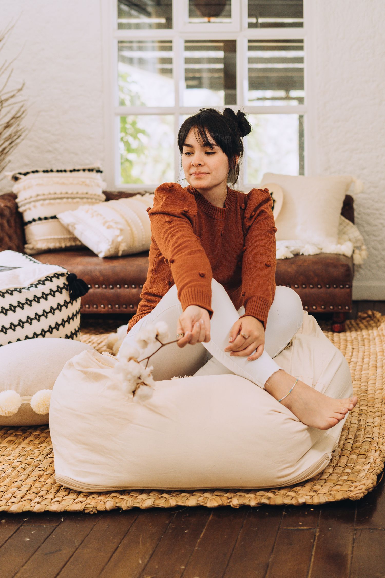 Cozy indoor scene with rust-colored sweater and white bean bag on natural jute rug.