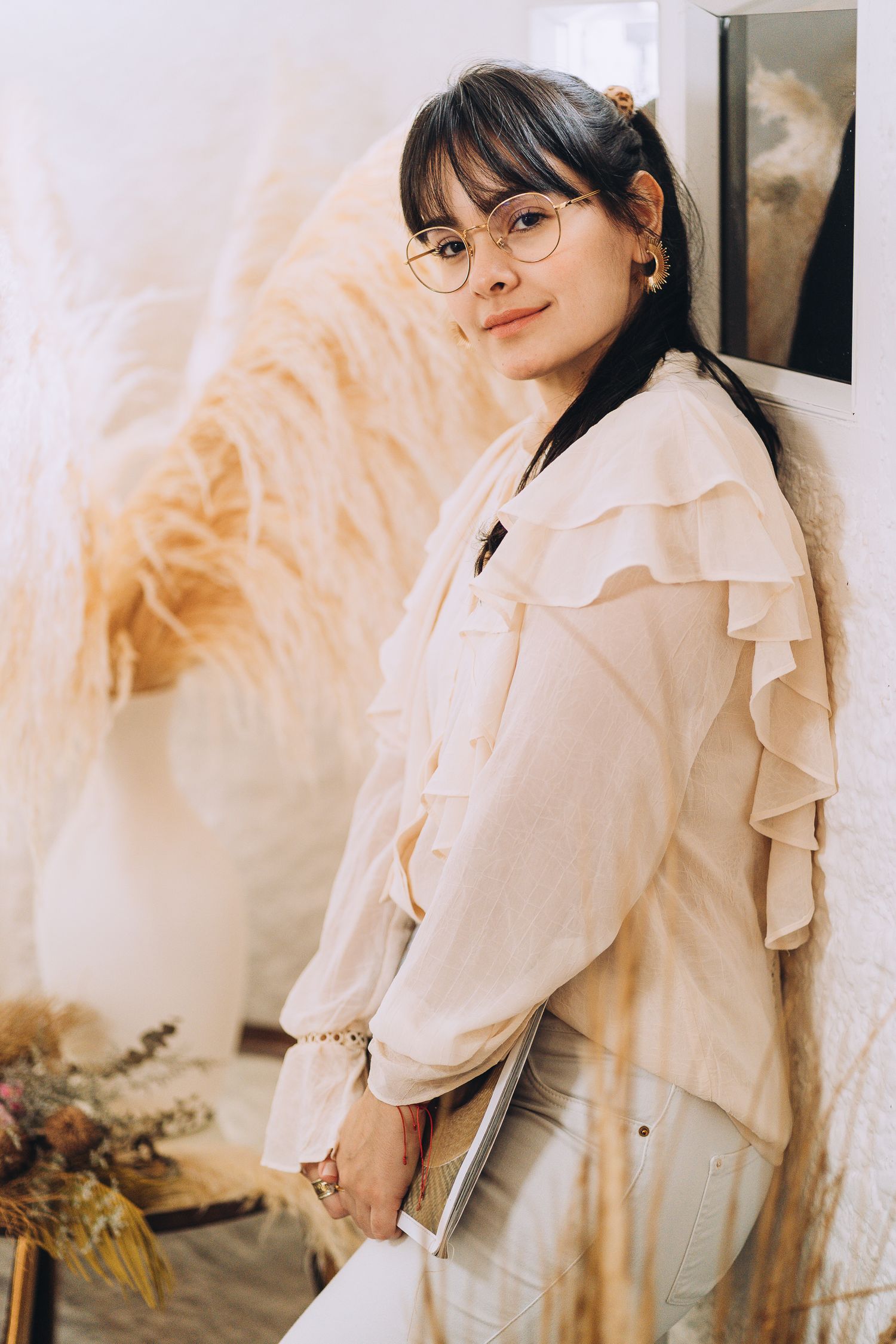 Bright lifestyle photo with ruffled white blouse and dried pampas grass decor.