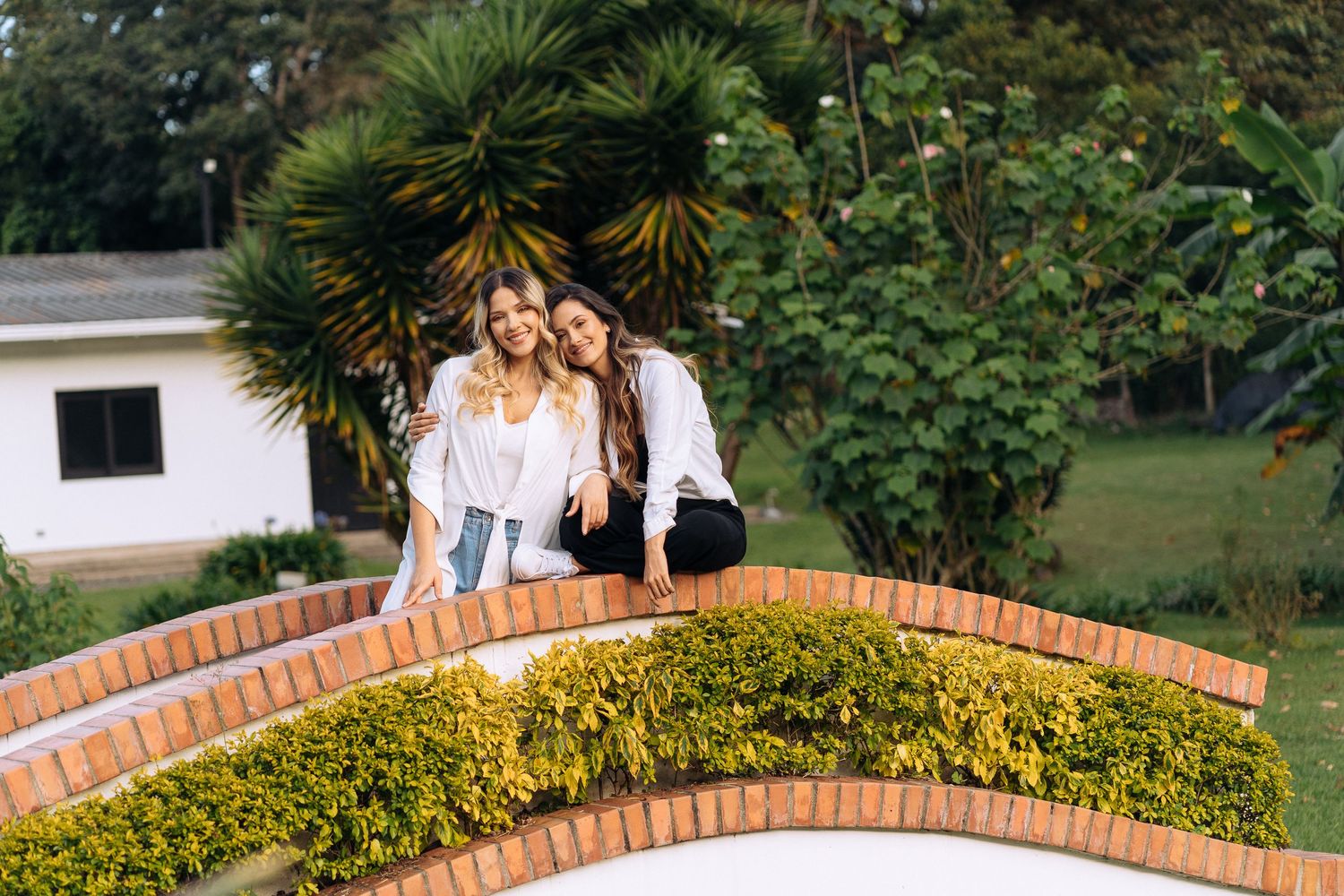 Candid shot of two people relaxing on a curved brick wall in a garden setting.