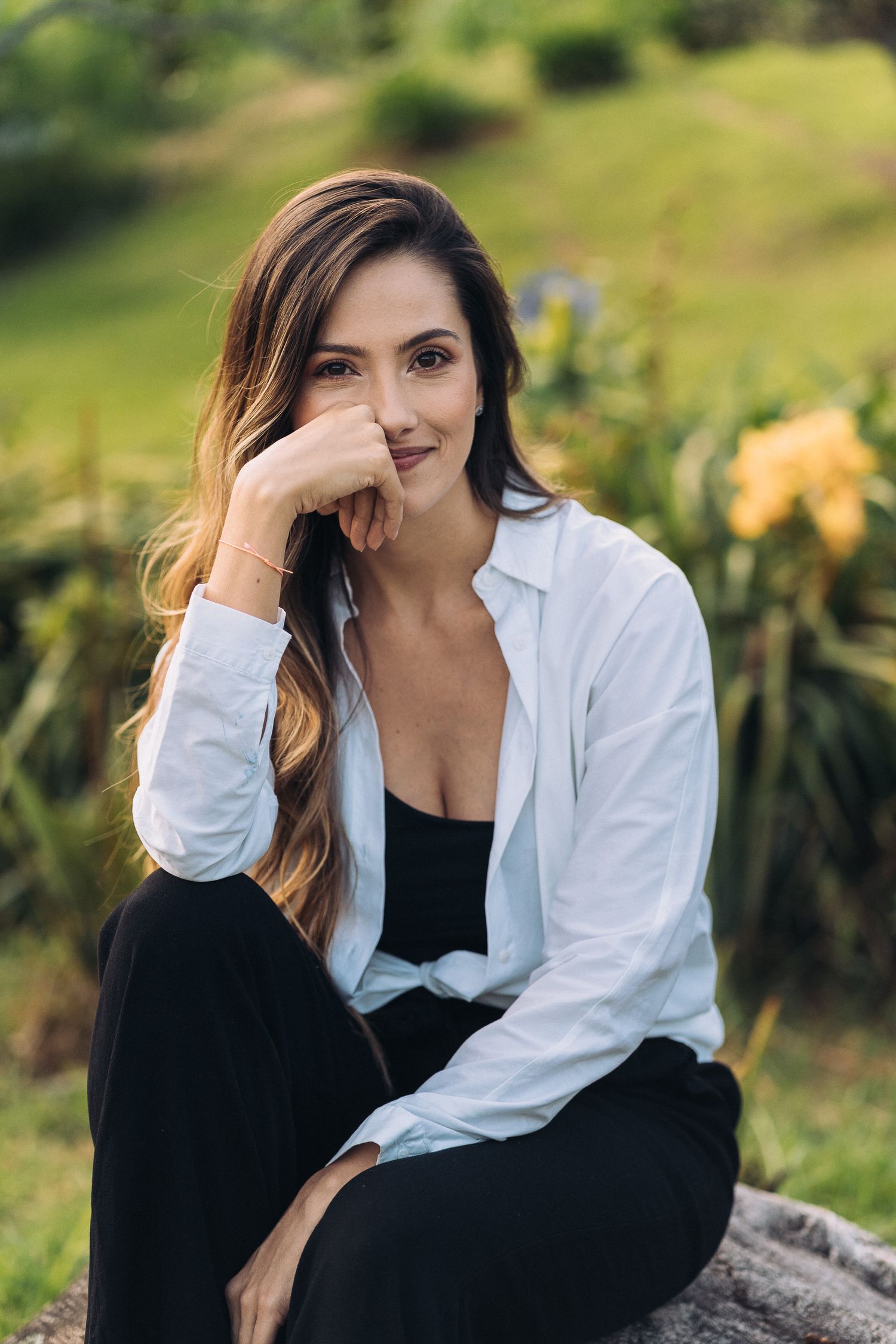Portrait shot in a garden setting wearing a white button-down shirt and black pants.
