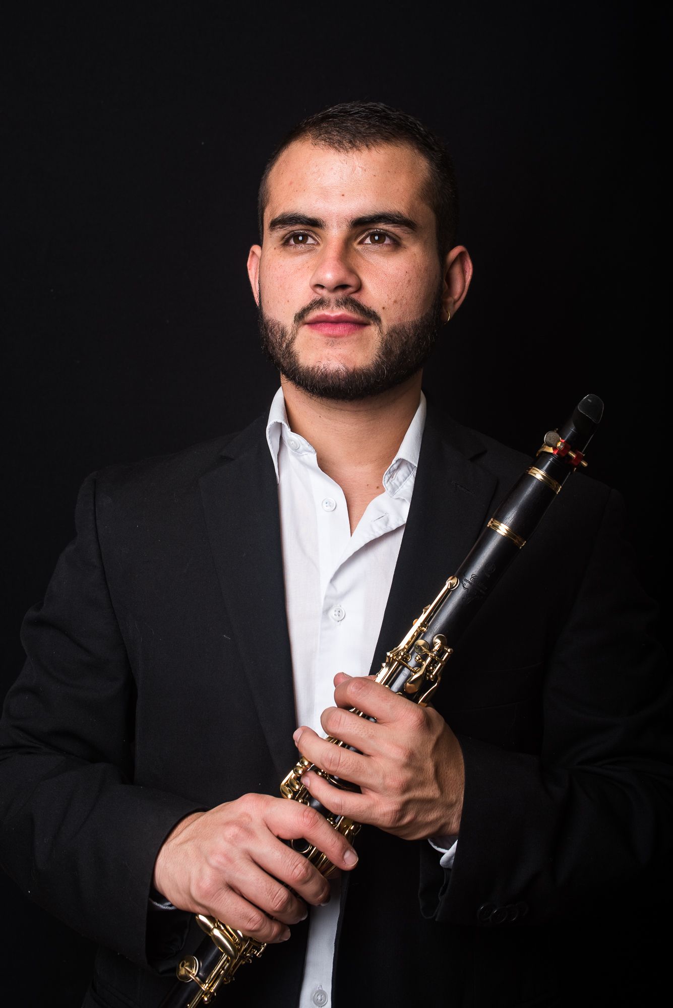 Professional studio portrait of classical musician posing with clarinet in formal attire.
