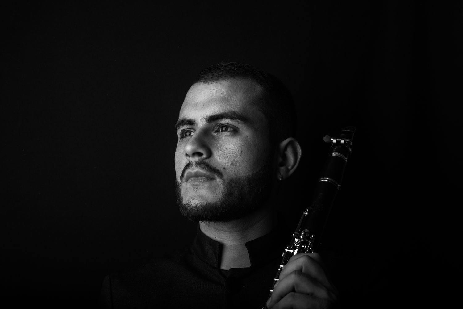 Moody low-key portrait of musician with clarinet in dramatic lighting.