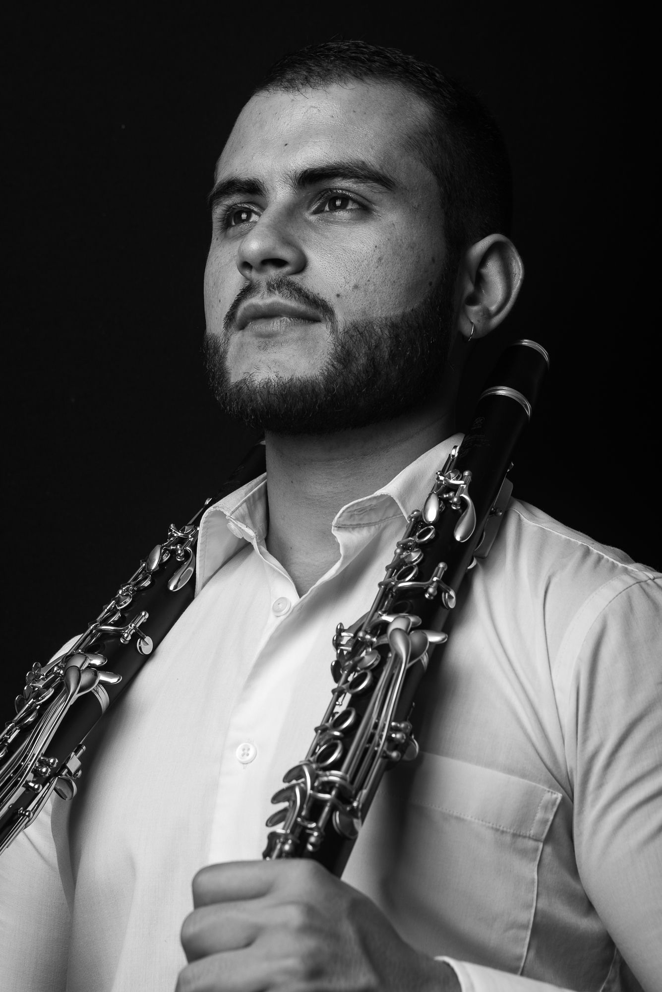 Artistic black and white studio portrait of musician posing with professional clarinet.