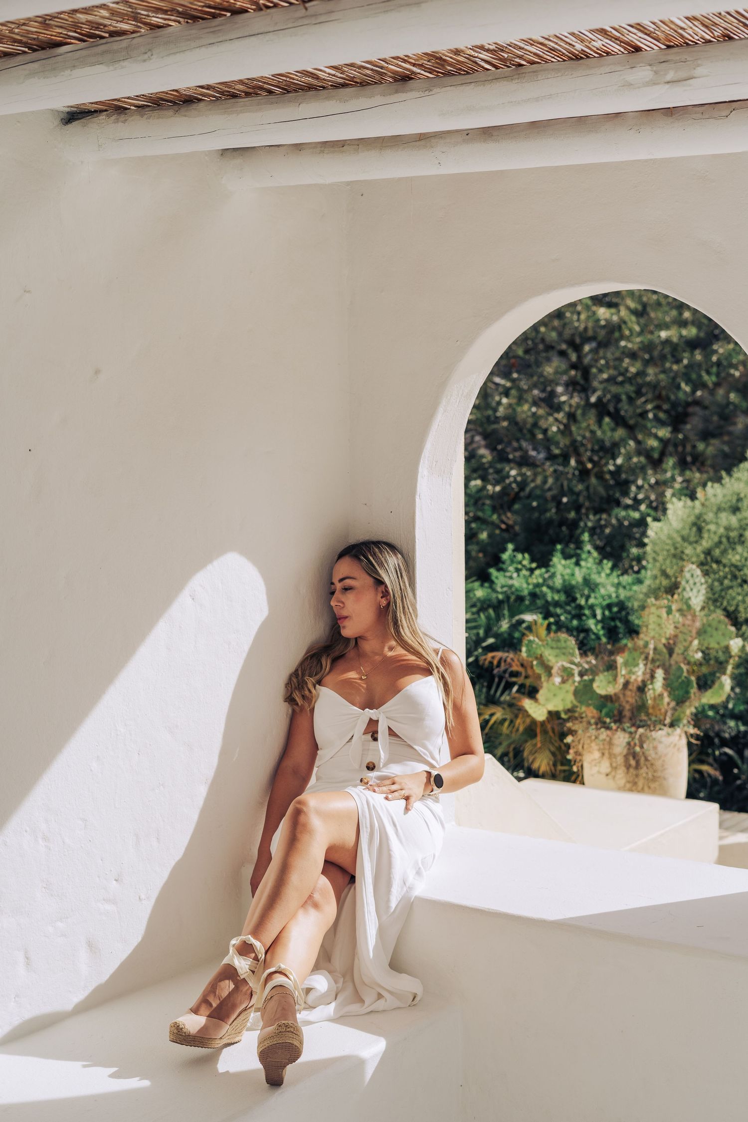 Sunlit Mediterranean-style porch with arched doorway and white walls.