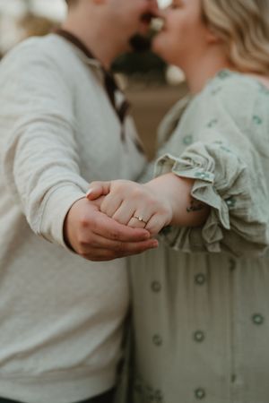 Close-up of an engaged couple holding hands and showing engagement rings during a couples session in Panama City Beach, Florida.