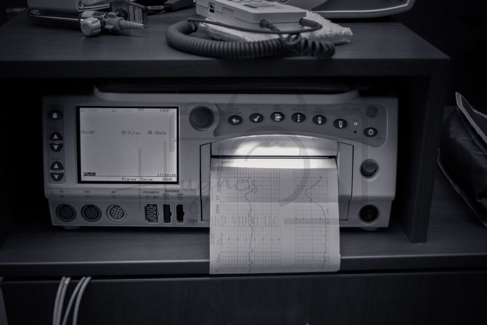 Medical monitoring equipment displays vital signs data in black and white.